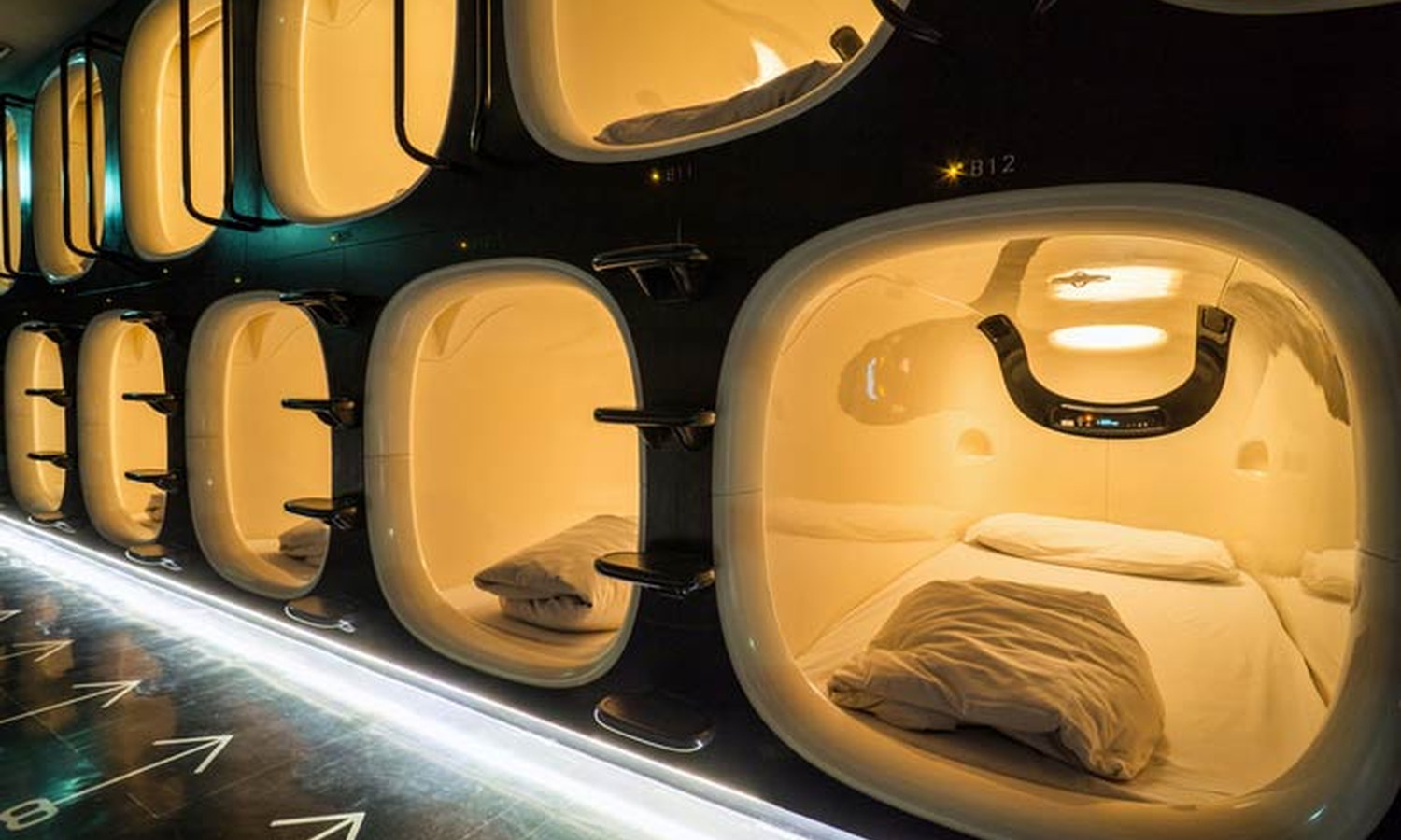 Row of compact capsule berths along a narrow corridor in a Japanese capsule hotel