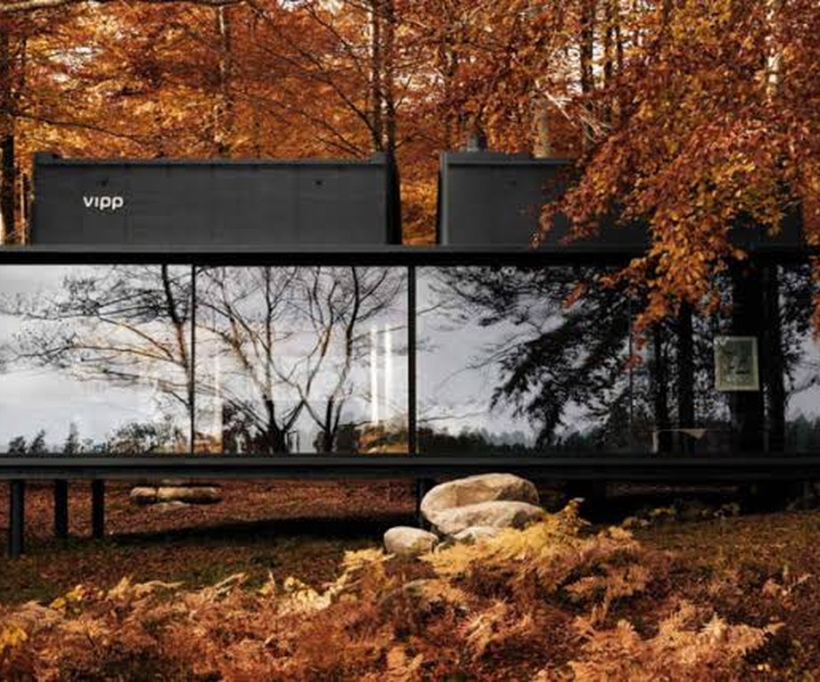 Steel and glass cabin with full-height windows at the edge of a Swedish lake