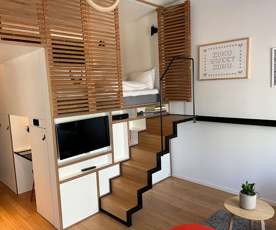 Amsterdam loft with a bed on a raised platform reached by a staircase above a work table