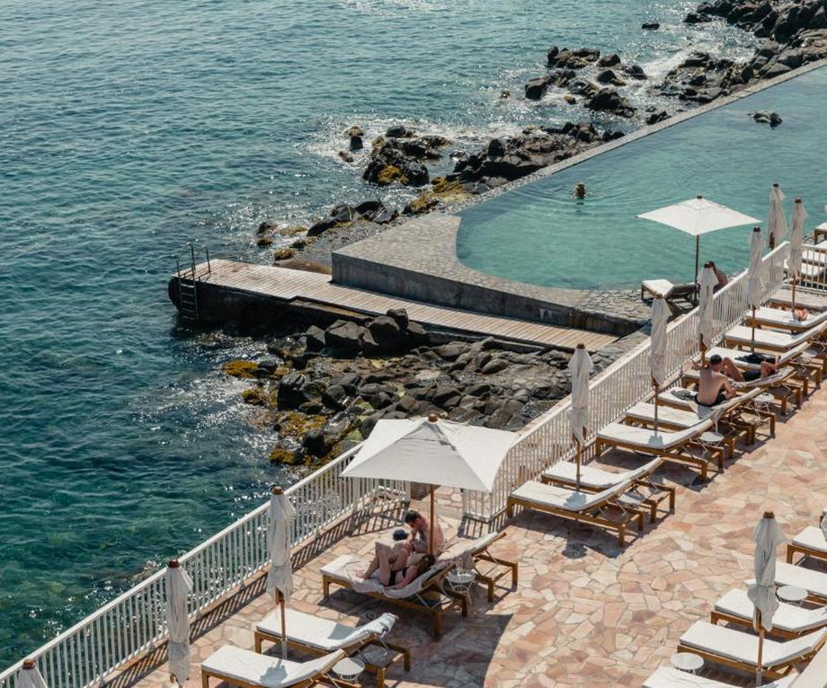 Low modernist hotel block on red coastal rock with a seawater pool cut into the stone