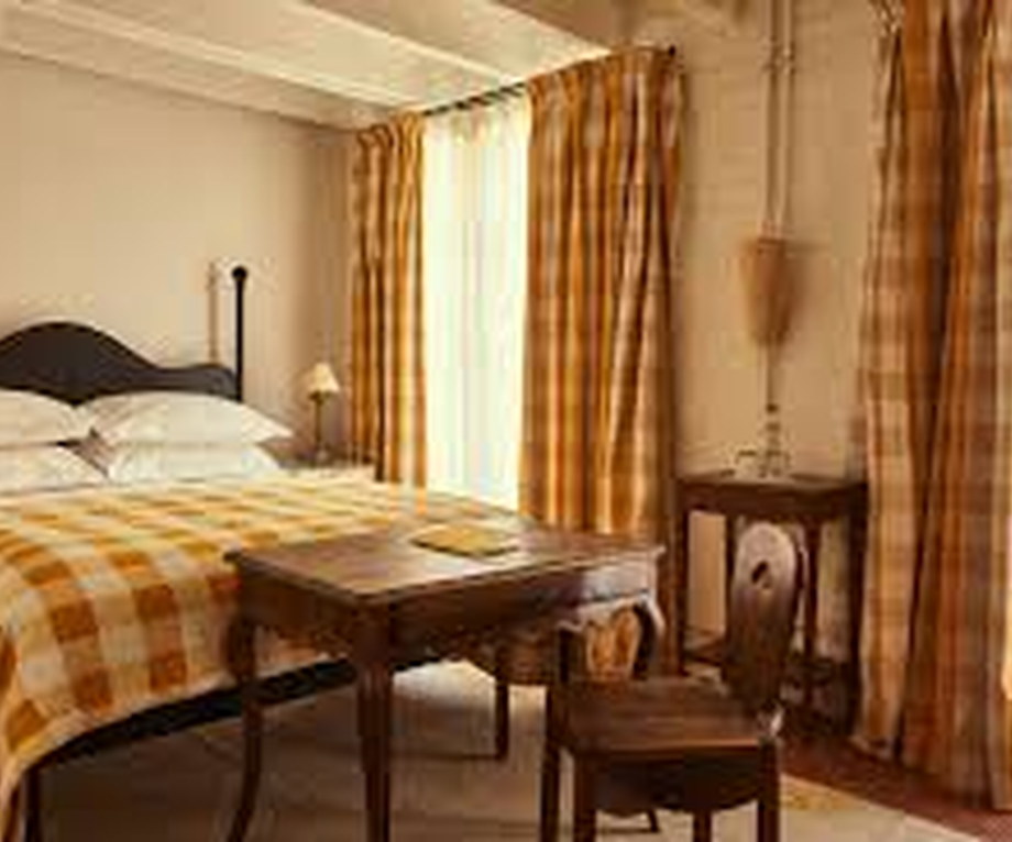 Plain guest room in a converted New Orleans schoolhouse with an antique bed and shuttered window