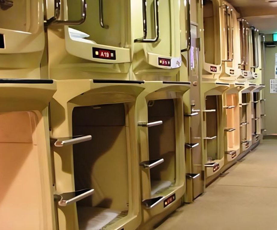 Rows of classic capsule berths on a Tokyo sleeping floor with lockers along the corridor